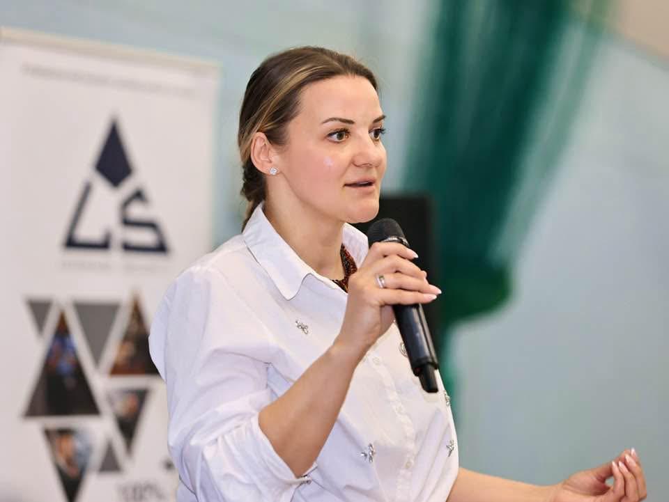 Kristina Culka speaking with a microphone during a charity training session