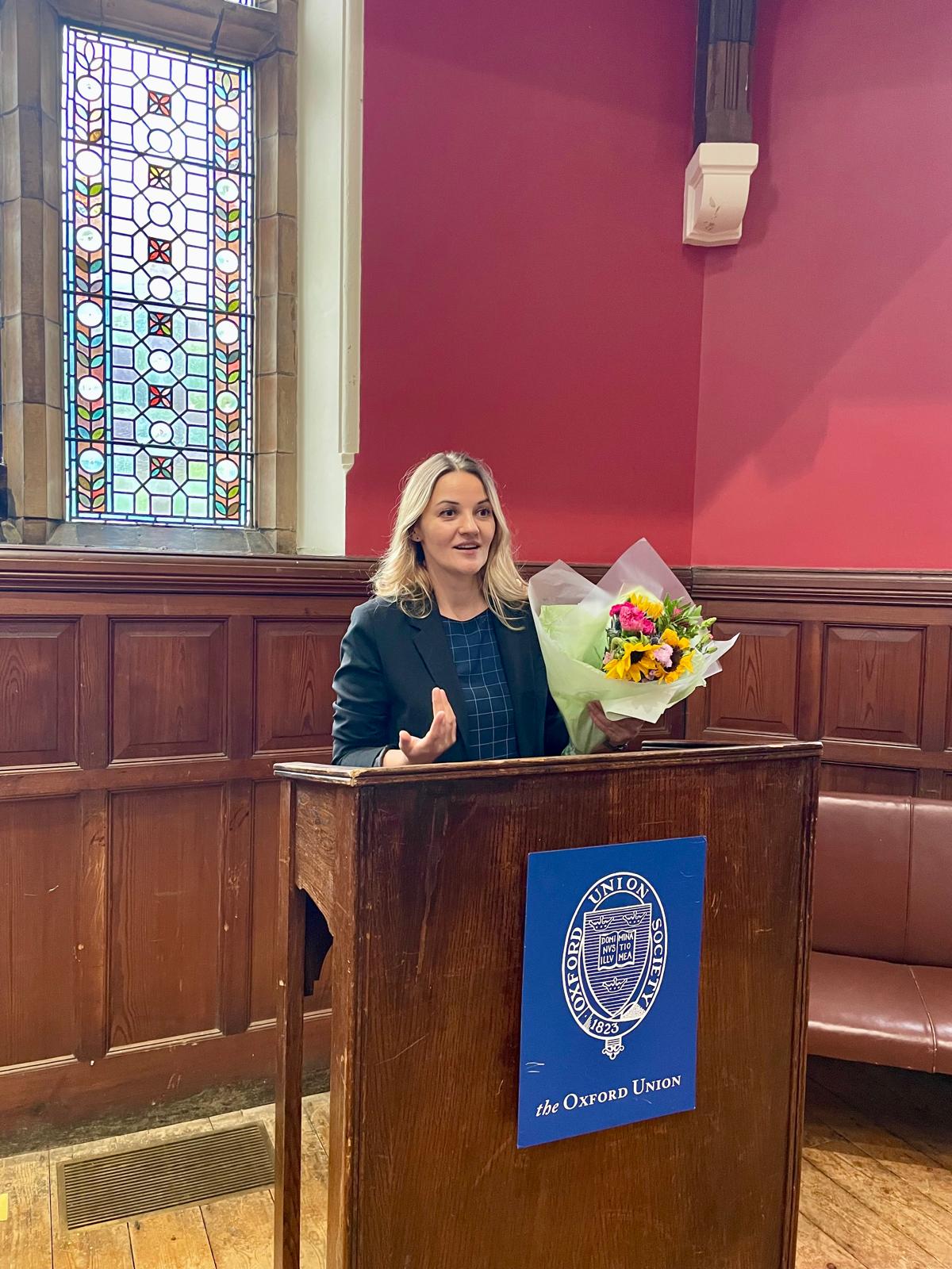 Kristina Culka speaking at the Oxford Union podium during a charity-related event
